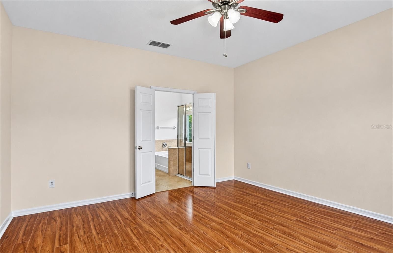 Additional view of the spacious primary bedroom, featuring freshly painted neutral walls, hardwood flooring, and a ceiling fan. - 2153 BARRACUDA CT, HOLIDAY