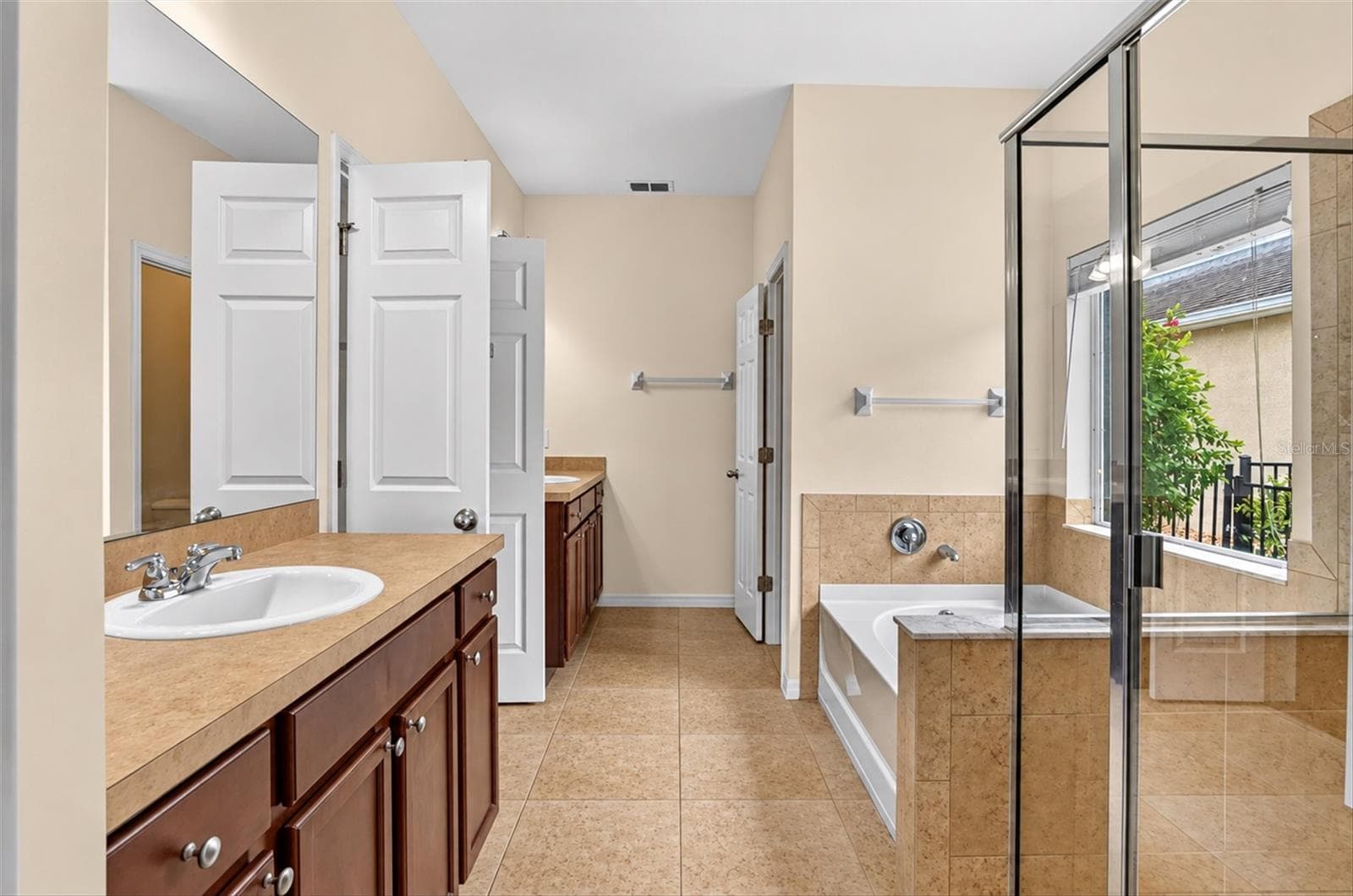 Primary bathroom with dual vanities, soaking tub, separate shower and natural light. - 2153 BARRACUDA CT, HOLIDAY