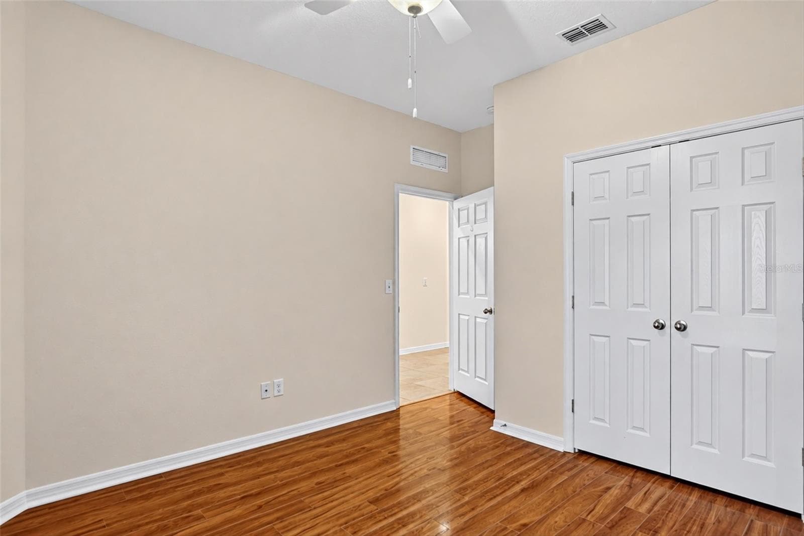 Additional bedroom view showcasing neutral walls and hardwood flooring. - 2153 BARRACUDA CT, HOLIDAY