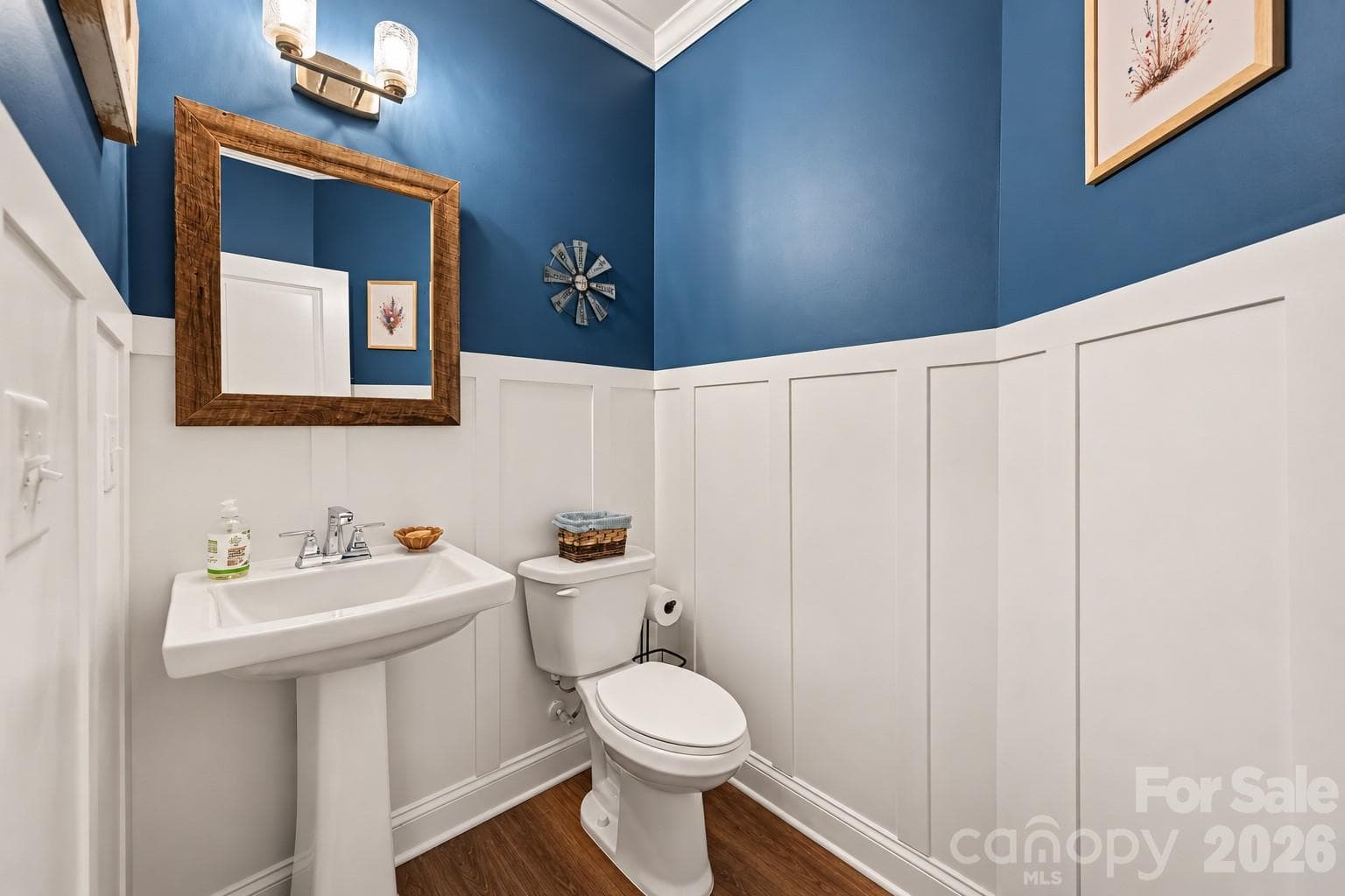 A powder room with bold blue walls and classic wainscoting. - 2703 Wedgewood Court, Denver