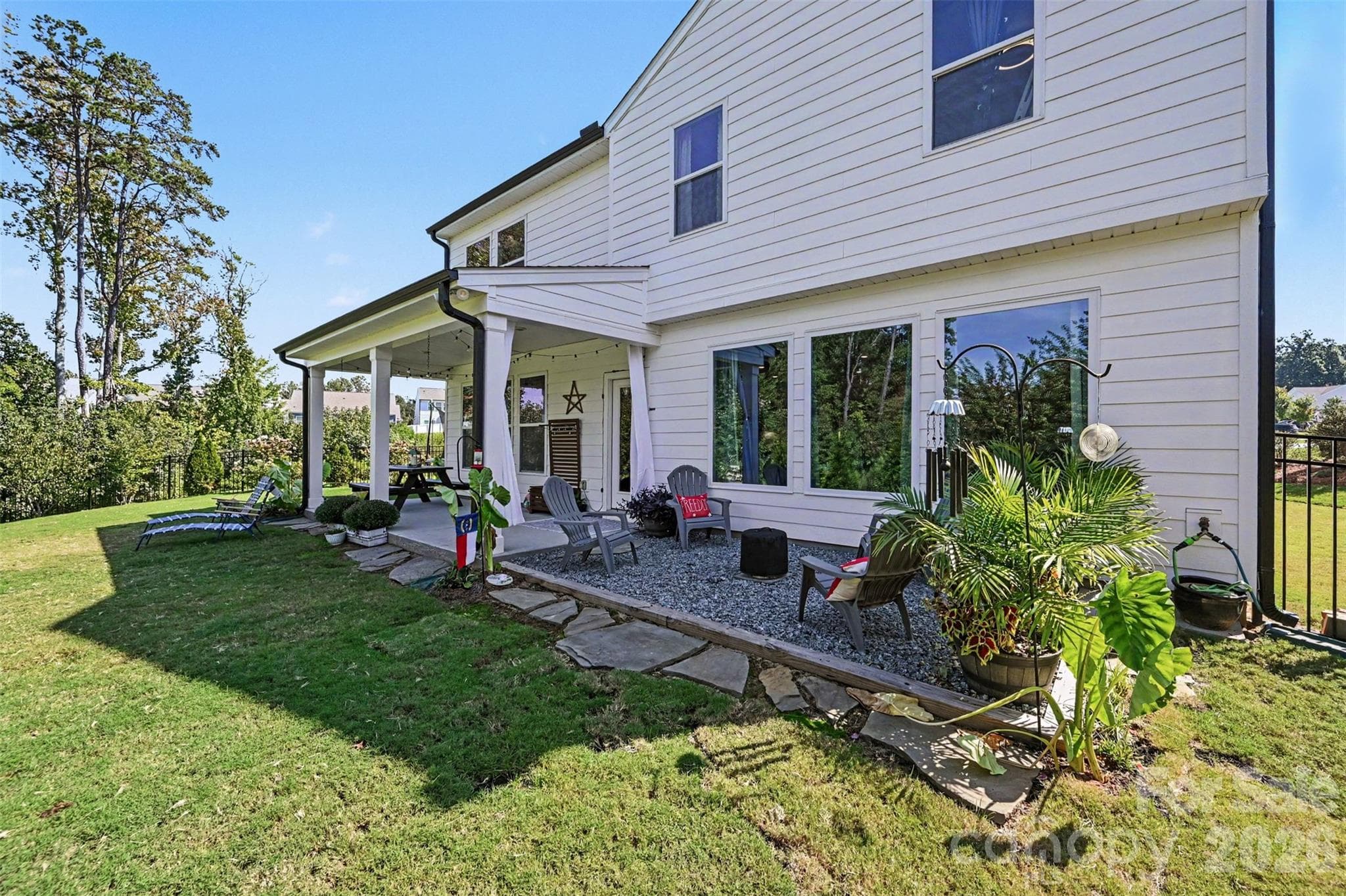 A spacious backyard with a covered porch and landscaped beds. - 2703 Wedgewood Court, Denver