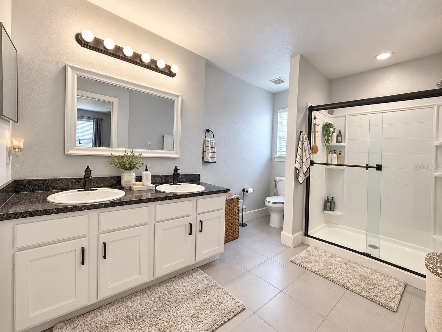Primary bathroom with dual sinks and glass-enclosed shower. - 3998 PEMBERLY PINES CIR, ST CLOUD