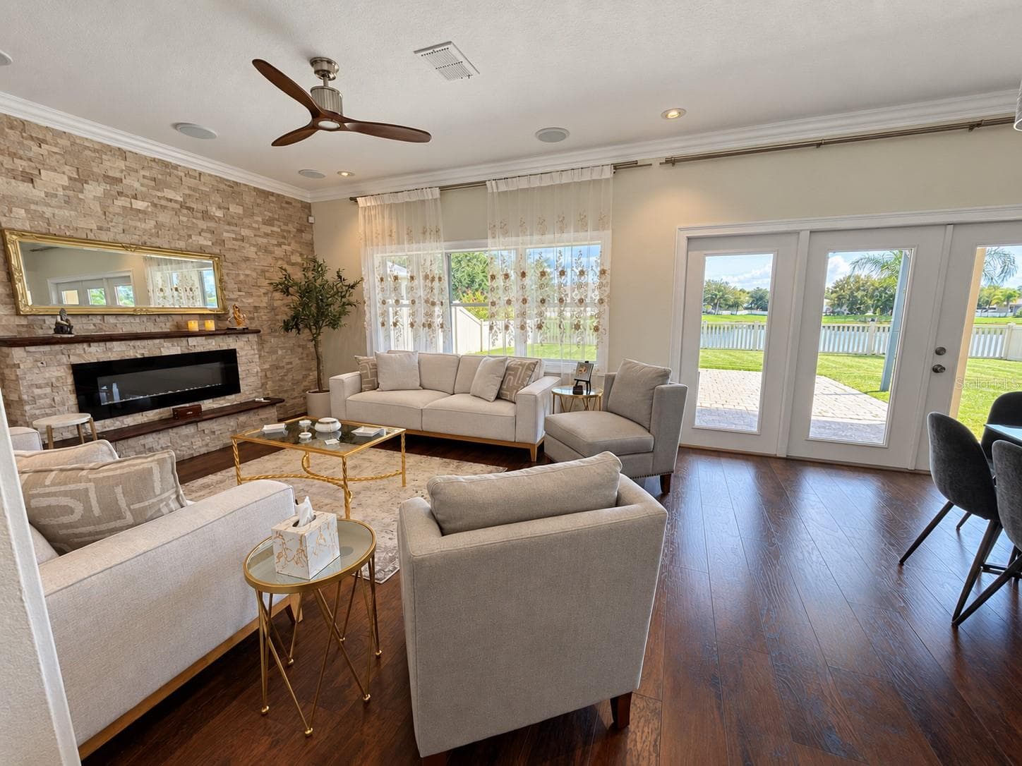 An inviting gathering space centered around a stone accent wall with a fireplace and mantel. Large windows bring in natural light, while the open layout connects easily to the kitchen and breakfast area. - 11117 ANCIENT FUTURES DR, TAMPA