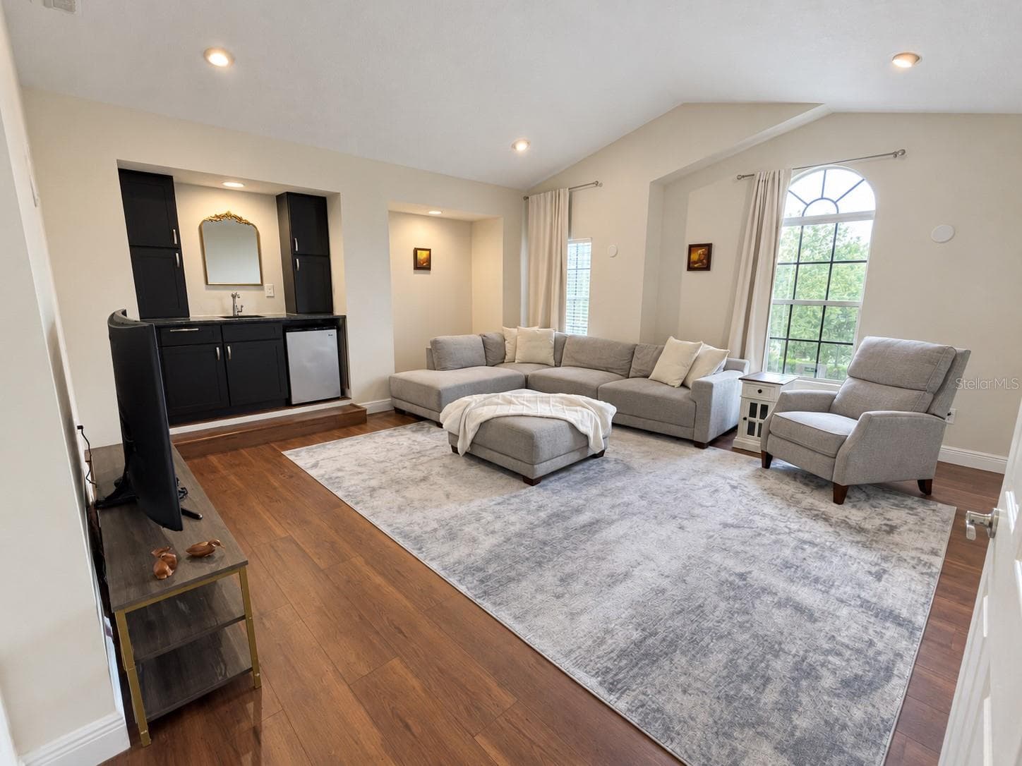 A spacious retreat with vaulted ceilings, tall windows, and room for a sectional and additional seating. A built-in wet bar with cabinetry and a compact refrigerator makes the room convenient for relaxing and entertaining. - 11117 ANCIENT FUTURES DR, TAMPA