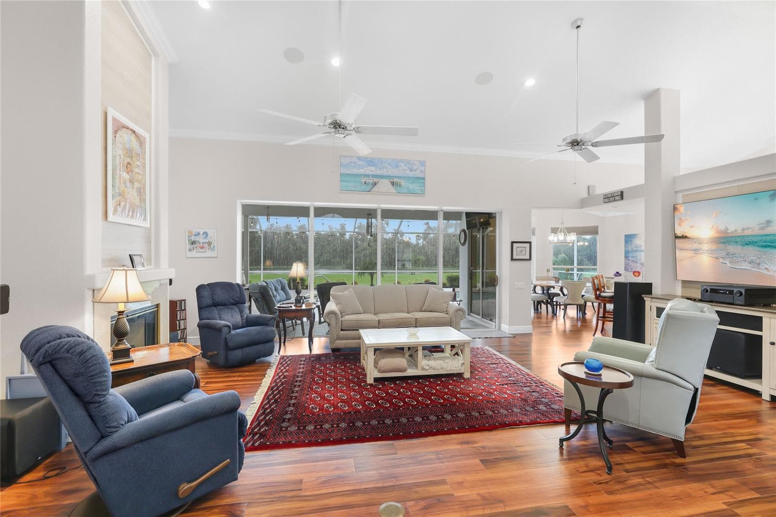 The great room has high ceilings, luxury vinyl plank flooring, six-inch crown molding, ceiling fans, and a poolside lake view - 3306 LITTLE COUNTRY RD, PARRISH