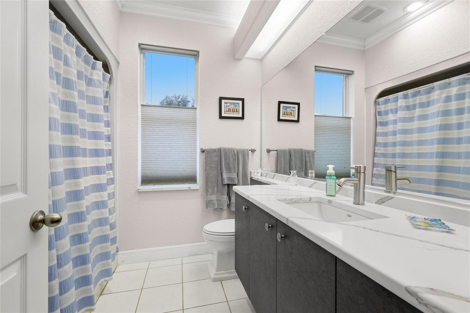 Guest bathroom features tile flooring, solid surface countertop, crown molding, updated plumbing fixtures, and Toto toilet. - 3306 LITTLE COUNTRY RD, PARRISH