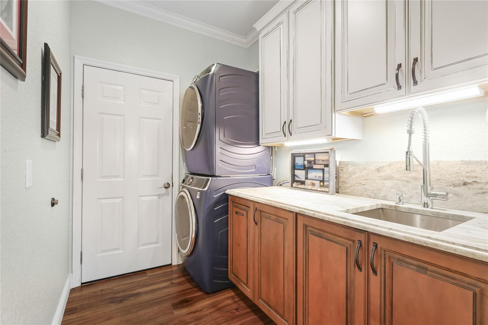 New laundry room featuring custom cabinetry, granite counter with backsplash, and stacked GE profile washer & dryer. - 3306 LITTLE COUNTRY RD, PARRISH