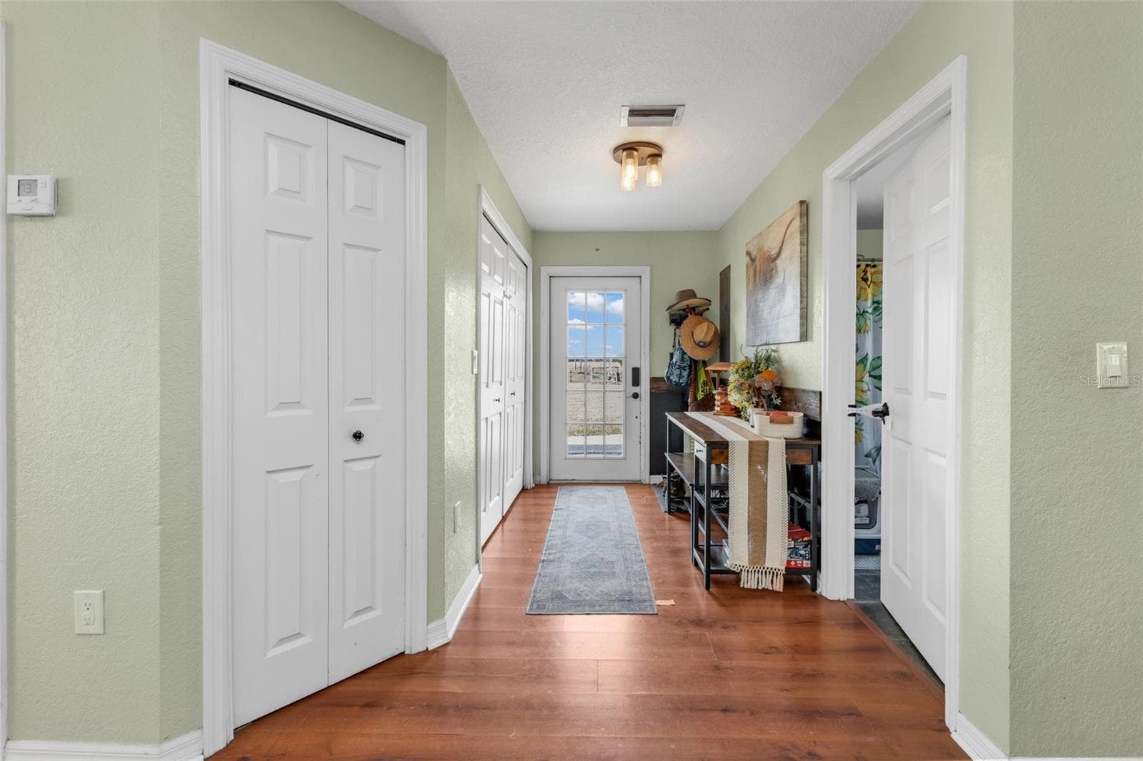Hall to side entry. Laundry closet on left and guest bathroom on right. - 3682 NW LIMESTONE HEIGHTS ST, ARCADIA