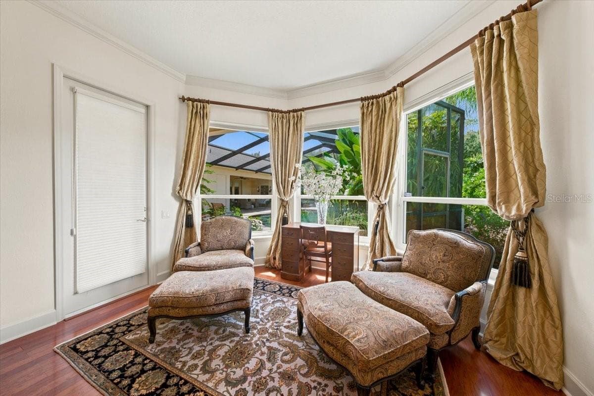 Private primary sitting area featuring rich hardwood floors, expansive windows framing outdoor views, and elegant drapery. - 5513 KEELER OAK ST, LITHIA