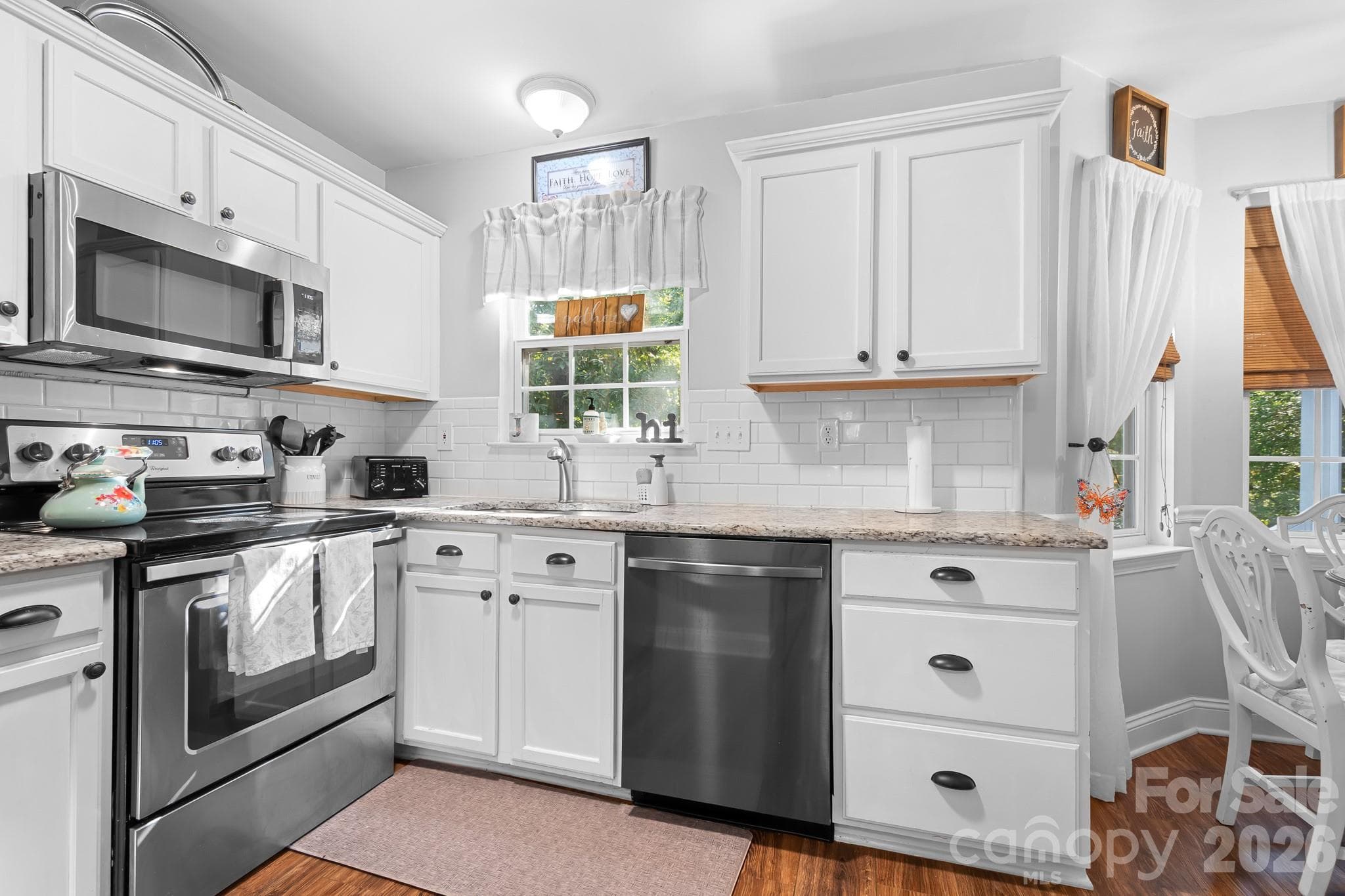 Kitchen with Granite Counters, Stainless appliances, built in microwave, smooth top stove, and sink with window overlooking backyard and woods. LVP Flooring in a beautiful warm tone wood shade. - 4126 Medford Drive NW, Concord