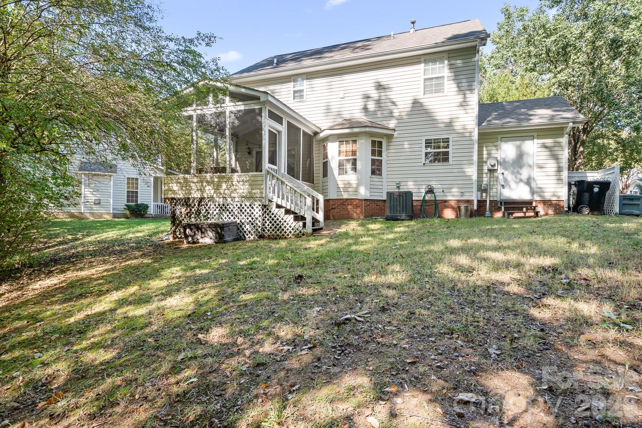 View from the back of the property looking at the backside of the home .Storage area on far right of house with shelving and water heater.  Good view of Screened porch and bay window in kitchen. - 4126 Medford Drive NW, Concord
