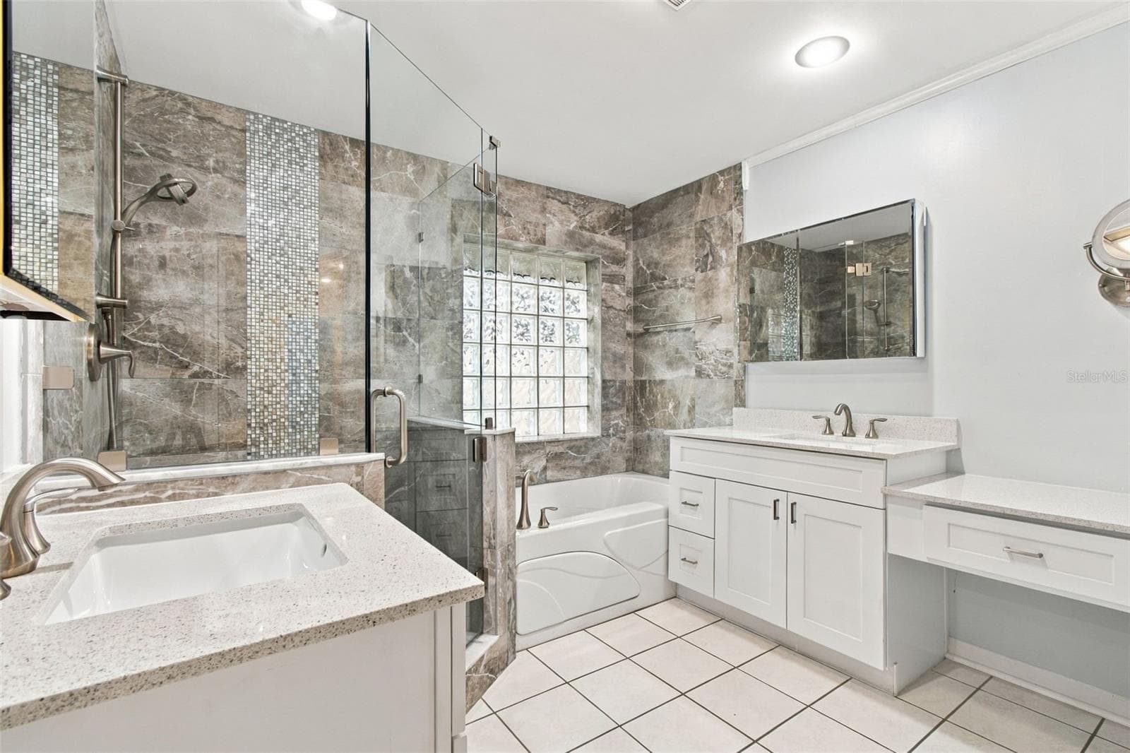 This primary, custom bathroom offers separate sinks, a makeup counter, a jetted spa tub, a large enclosed glass shower, and a water closet (toilet room). - 2254 HERON CIR, CLEARWATER