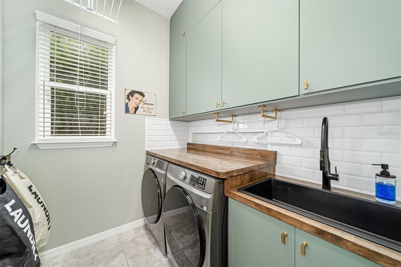 Thoughtfully designed laundry room with a utility sink and custom folding racks. - 6195 ANISE DR, SARASOTA