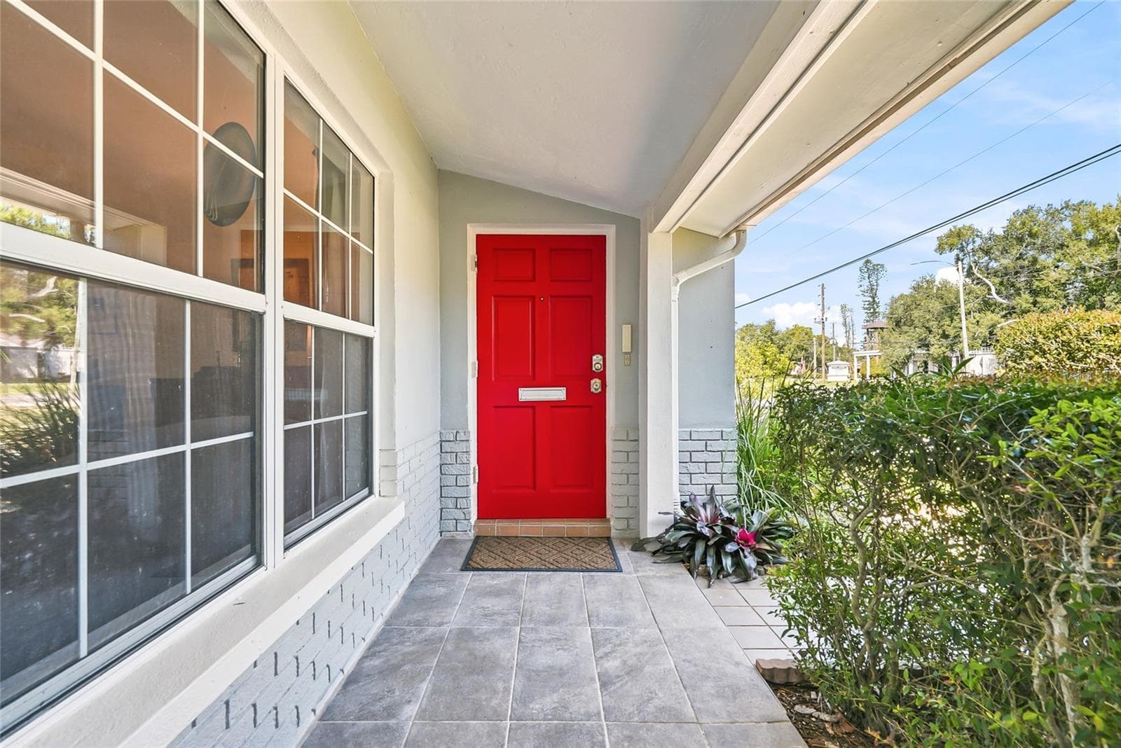 Step inside through a cheerful red front door, tucked beneath a covered, tiled porch framed by beautiful landscaping. - 1890 62ND AVE S, ST PETERSBURG