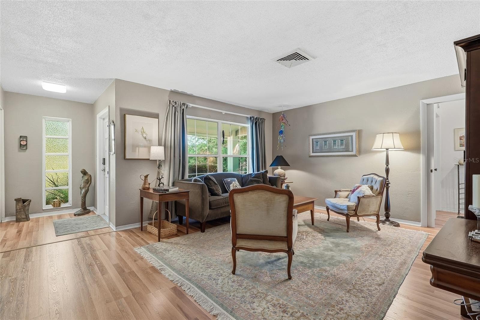 Natural light and garden views bring warmth to the front living room, creating an inviting setting for conversation or a quiet afternoon. - 1890 62ND AVE S, ST PETERSBURG