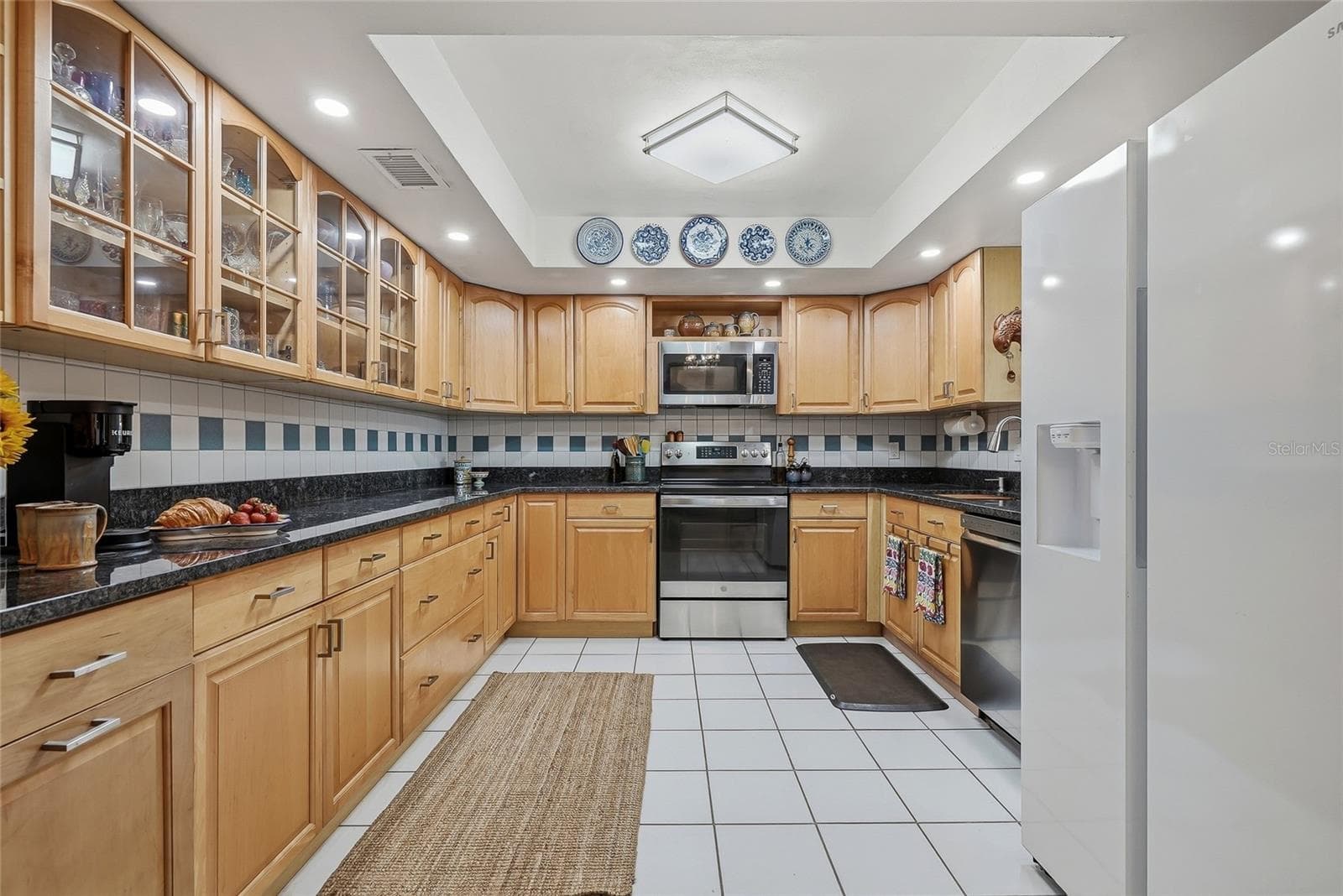 Spread out and create in a kitchen featuring generous counter space, abundant cabinetry, and glass-front cabinets to showcase your favorite pieces. - 1890 62ND AVE S, ST PETERSBURG