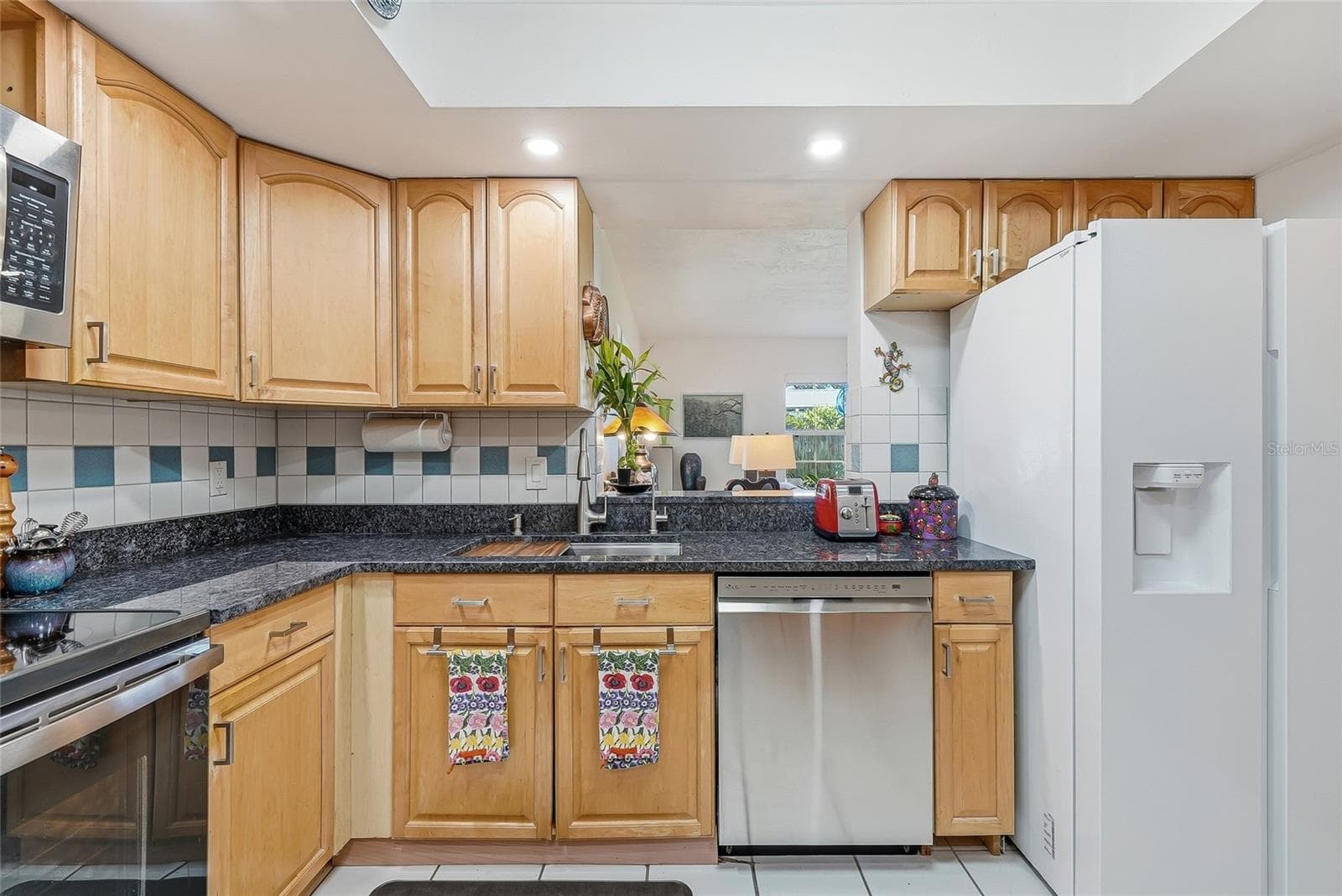 Everything within reach, with wraparound counters, plentiful cabinet storage, and a convenient pass-through connecting the kitchen to the family room. - 1890 62ND AVE S, ST PETERSBURG