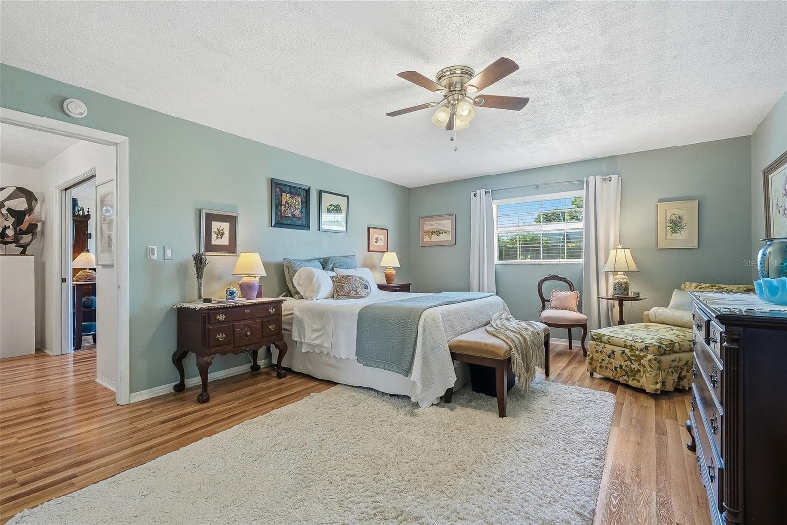 More than a place to sleep, this spacious primary bedroom offers room for a cozy reading corner beside the window. - 1890 62ND AVE S, ST PETERSBURG