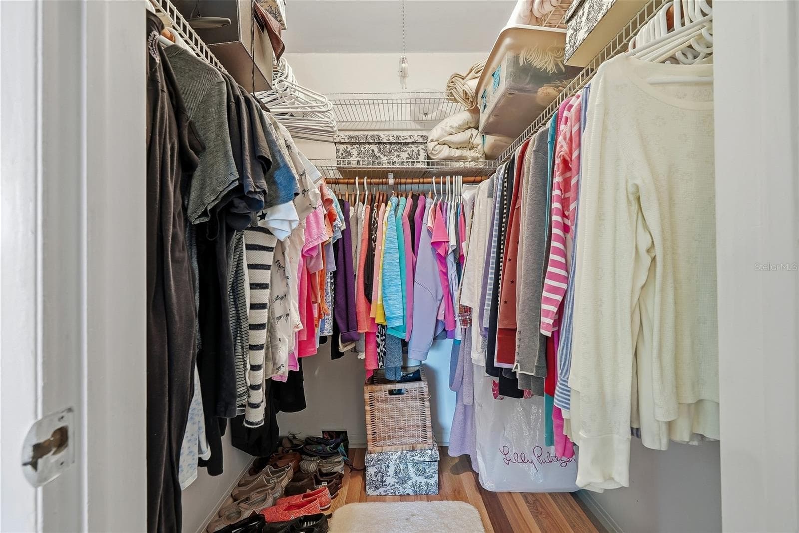 Keep your wardrobe within easy reach in a walk-in closet featuring hanging space on three sides and overhead shelving for extra storage. - 1890 62ND AVE S, ST PETERSBURG