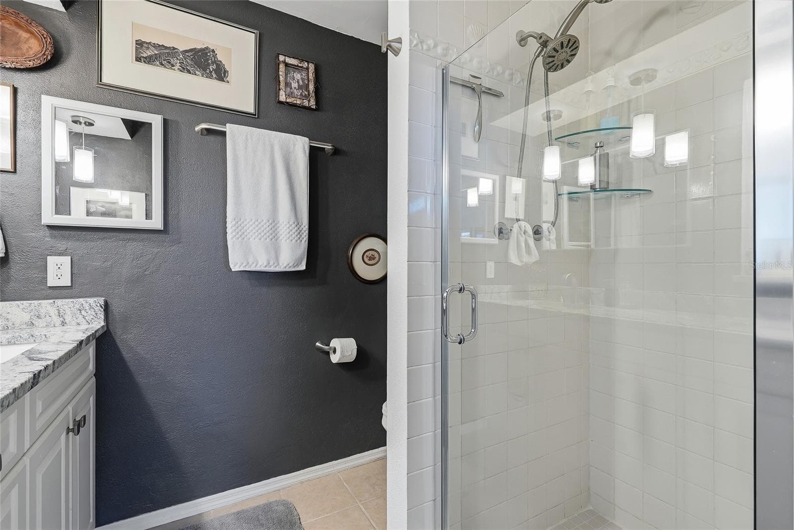 The primary bath features a glass-enclosed shower with classic white tile, glass corner shelves, and a convenient handheld showerhead. - 1890 62ND AVE S, ST PETERSBURG