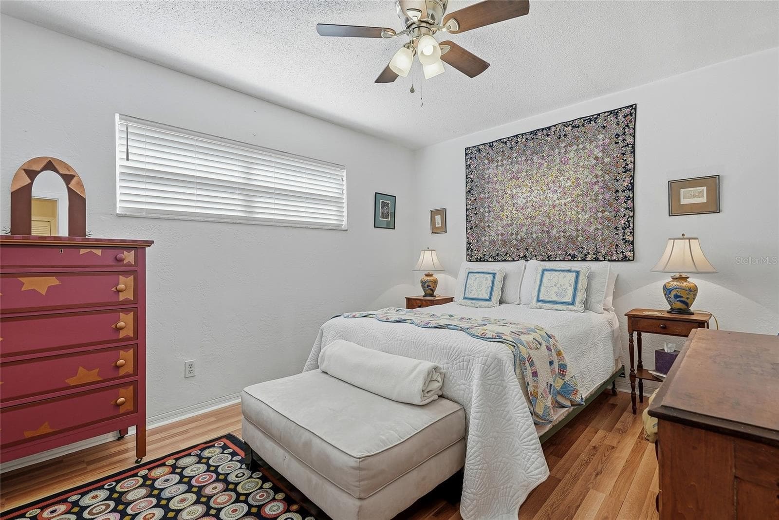 A welcoming second bedroom with soft neutral tones, warm wood-look flooring, and a wide window offers an inviting place to settle in. - 1890 62ND AVE S, ST PETERSBURG
