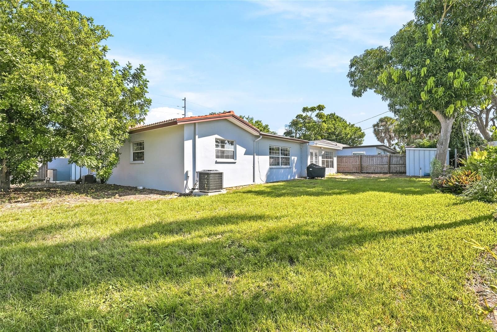 Room to enjoy the outdoors, with a broad backyard lawn and mature trees creating an inviting setting for gardening, games, or weekend gatherings. - 1890 62ND AVE S, ST PETERSBURG