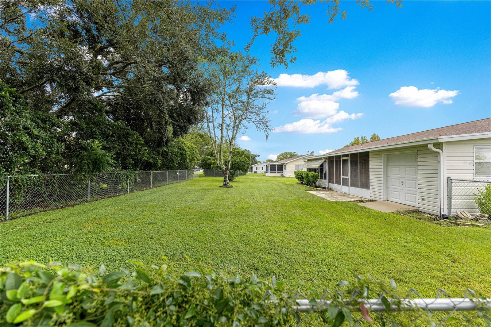 FENCED IN BACKYARD SHOWING BACK OF THE HOUSE AND GOLF-CART GARAGE - 10434 SE 178TH PL, SUMMERFIELD