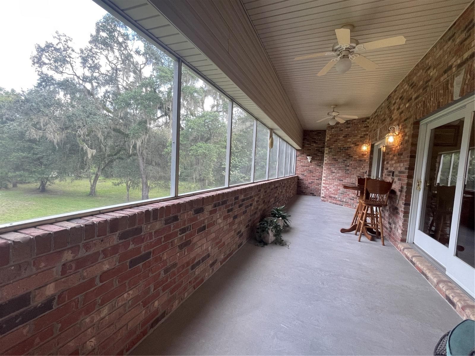Screened balcony has two sets of sliding glass doors leading to both the primary bedroom and living room - 5422 CYRIL DR, DADE CITY