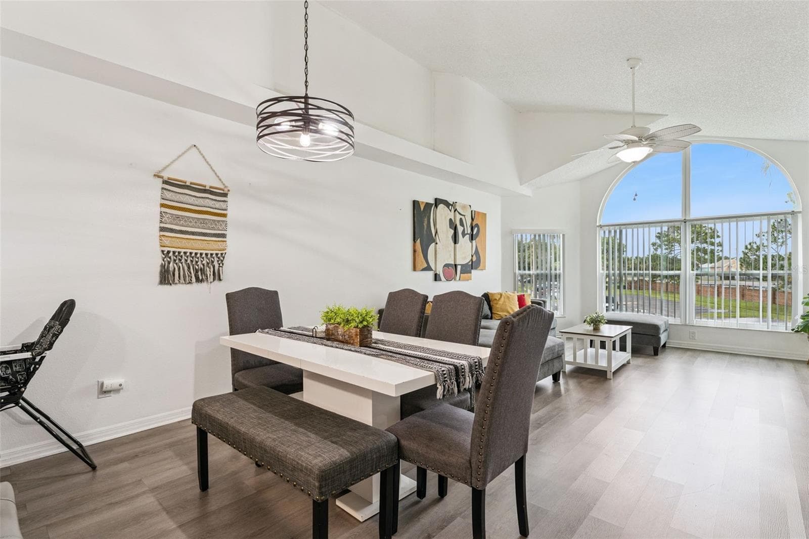 Dining Area: Dining space featuring an overhead modern chandelier fixture, dining table with bench seating, and smooth flow into the main living room. - 5017 LAGUNA BAY CIR #100, KISSIMMEE