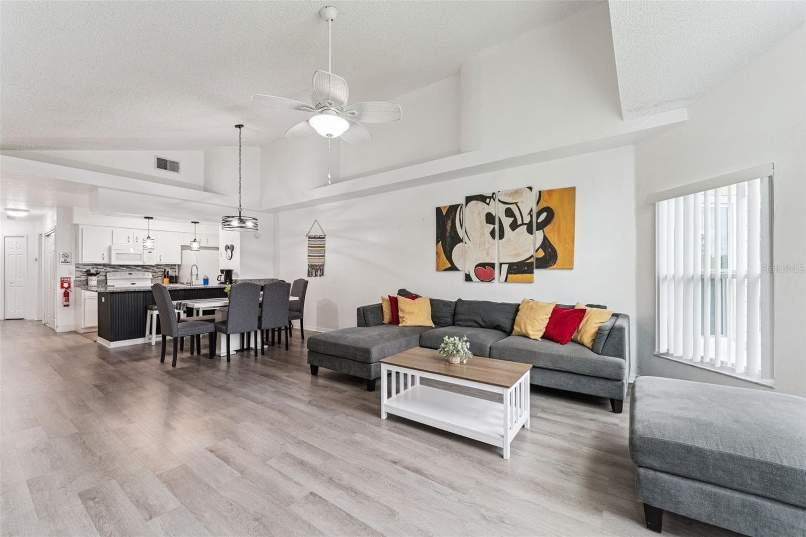 Open-Concept Living & Dining: Open-plan main floor seamlessly connecting the spacious living area, dining space, and adjacent kitchen under vaulted ceilings. - 5017 LAGUNA BAY CIR #100, KISSIMMEE
