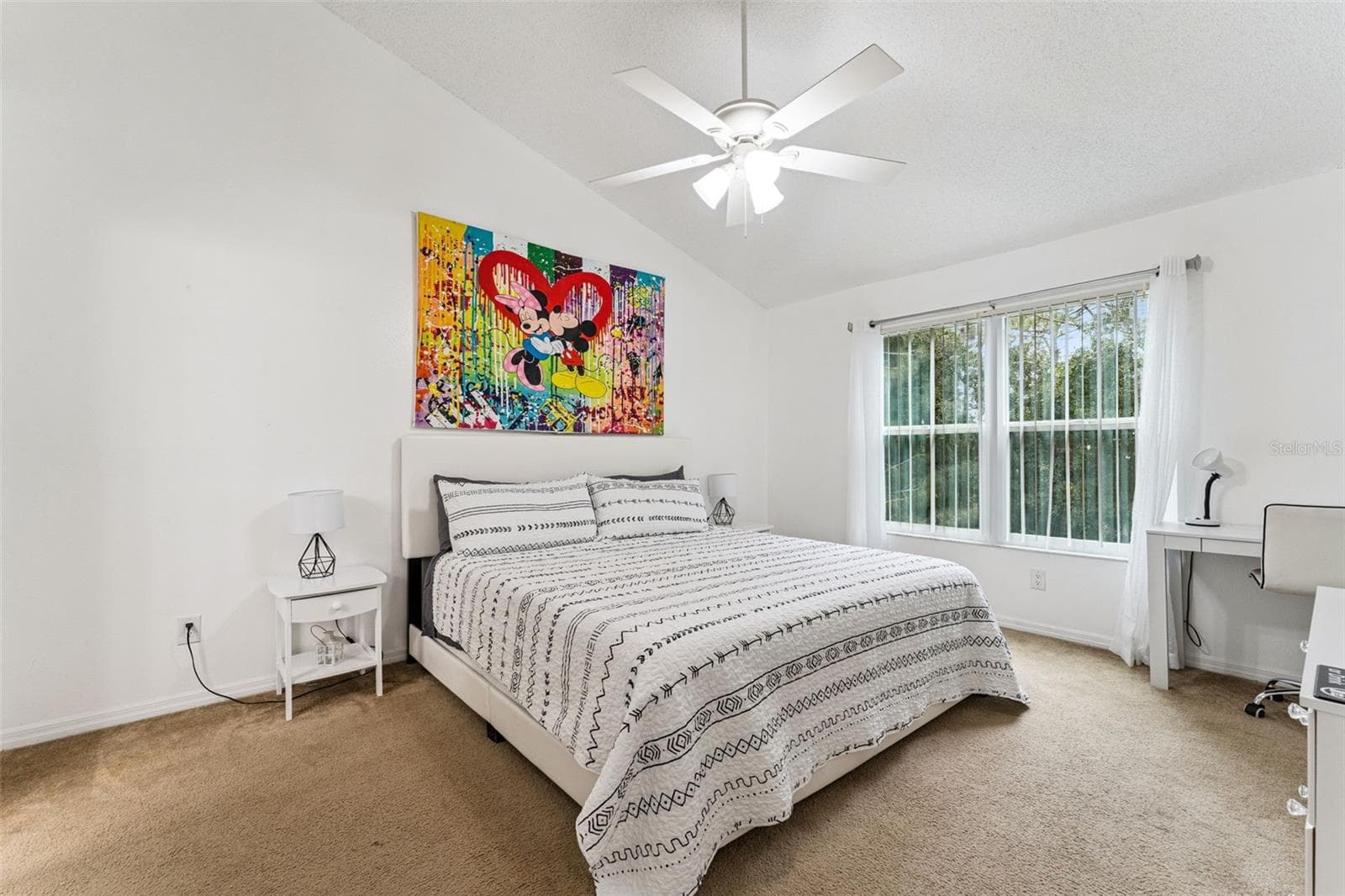 Primary Suite Alternate Angle: Spacious primary suite showing room for a king bed, nightstands, decorative wall art, and cozy carpet flooring under high ceilings. - 5017 LAGUNA BAY CIR #100, KISSIMMEE