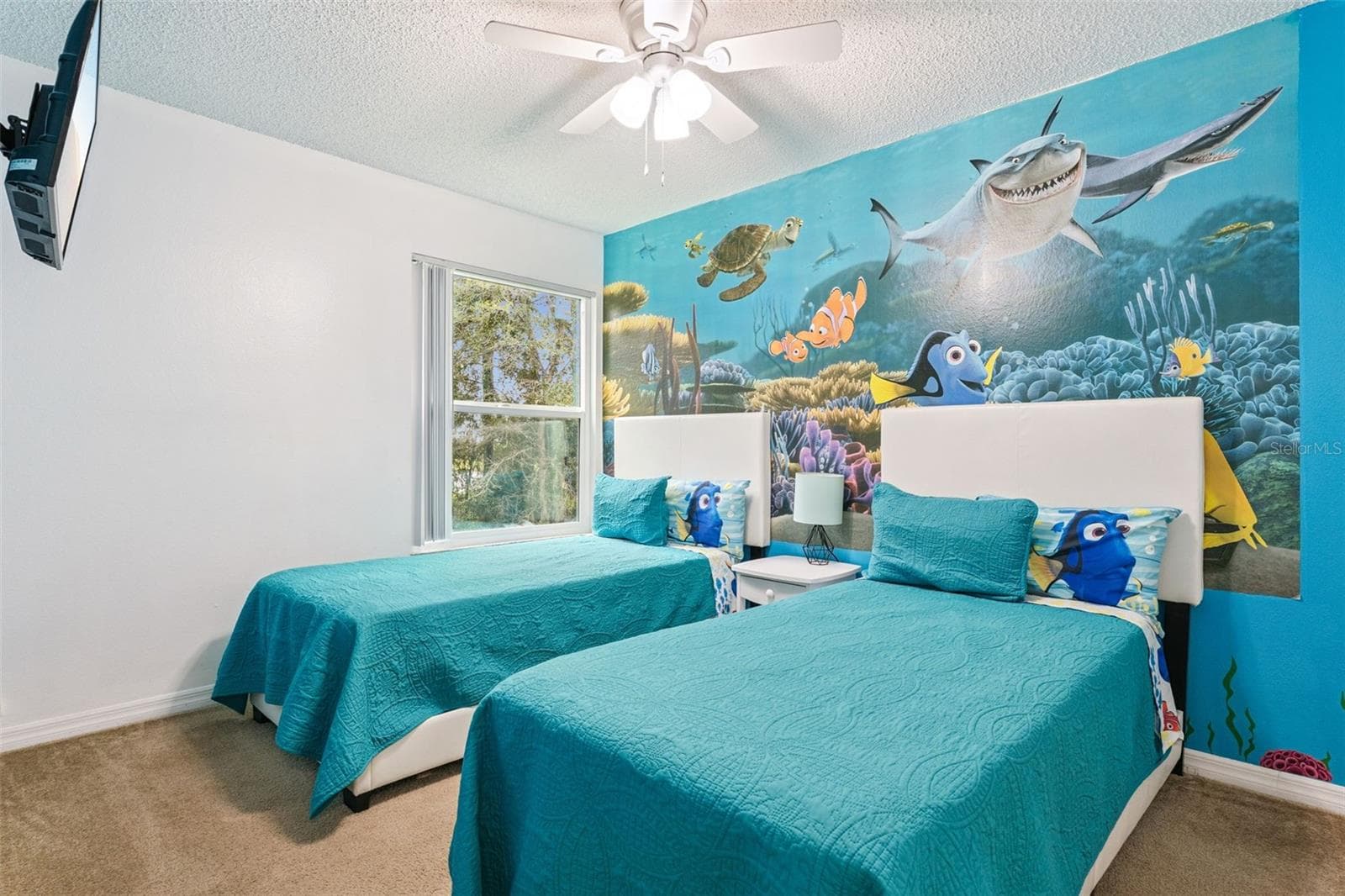Underwater-Themed Twin Bedroom: Fun themed guest bedroom with dual twin beds, vibrant ocean wall mural, ceiling fan, carpet flooring, and wall-mounted TV. - 5017 LAGUNA BAY CIR #100, KISSIMMEE