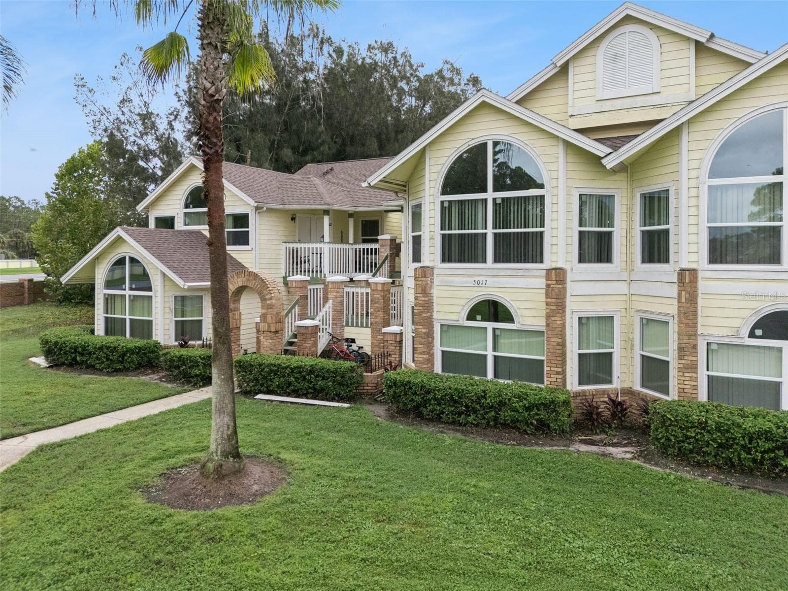 Exterior Elevation: Dynamic exterior angle displaying distinctive window styling, palm trees, and covered staircase entryways. - 5017 LAGUNA BAY CIR #100, KISSIMMEE