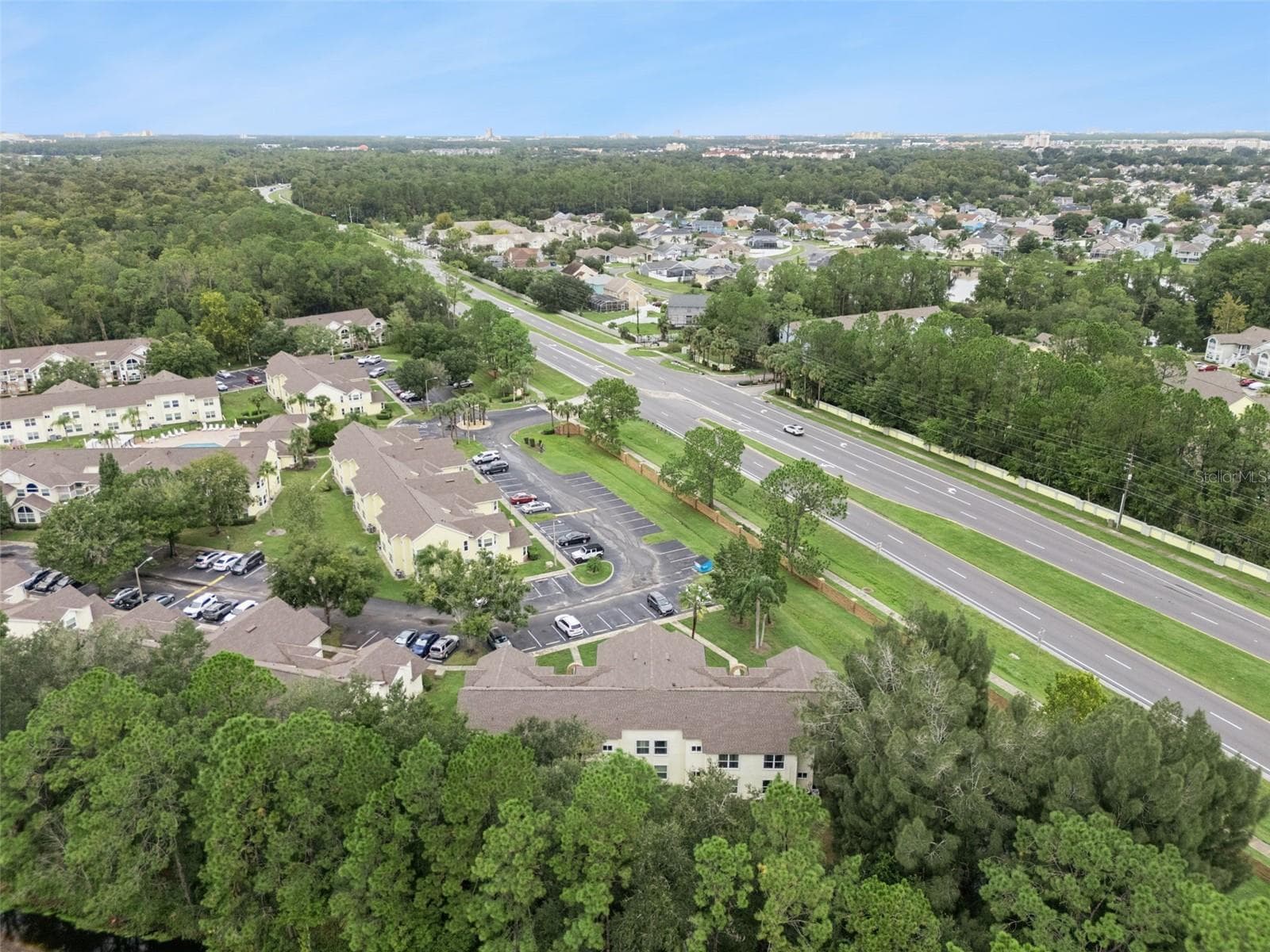 Regional Aerial Perspective: High-altitude aerial view highlighting the property's convenient position along major local roadways surrounded by mature greenery. - 5017 LAGUNA BAY CIR #100, KISSIMMEE