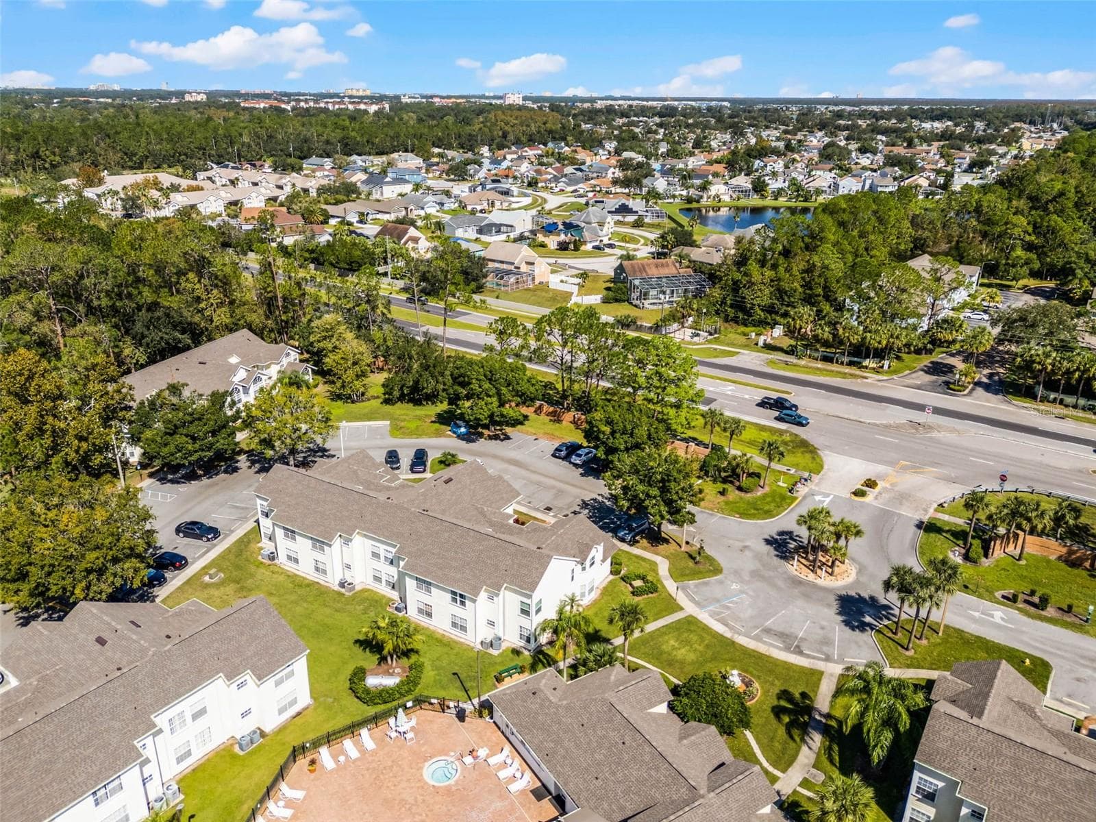 Entrance & Pool Area Aerial: Aerial view highlighting the community entrance loop, ample resident parking, clubhouse pool deck, and surrounding local neighborhood. - 5017 LAGUNA BAY CIR #100, KISSIMMEE