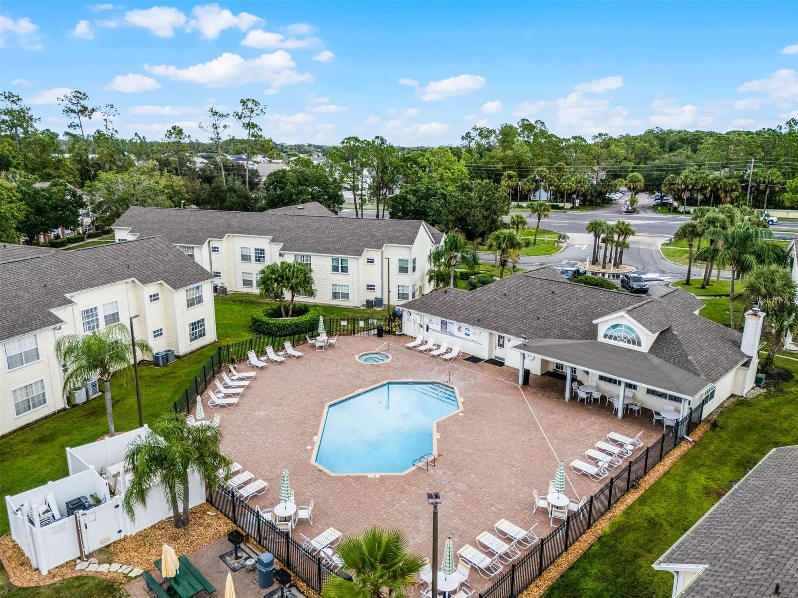 Clubhouse & Pool Grounds: Aerial perspective featuring the community clubhouse, covered poolside pavilion, spacious sun deck, and surrounding residential villas - 5017 LAGUNA BAY CIR #100, KISSIMMEE