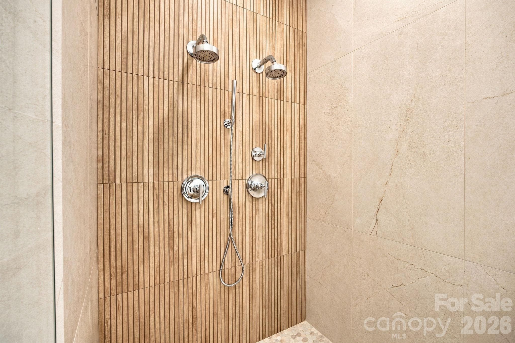 A luxurious primary walk-in shower featuring dual shower heads for an upscale, spa-like experience. - 18416 Peninsula Club Drive, Cornelius