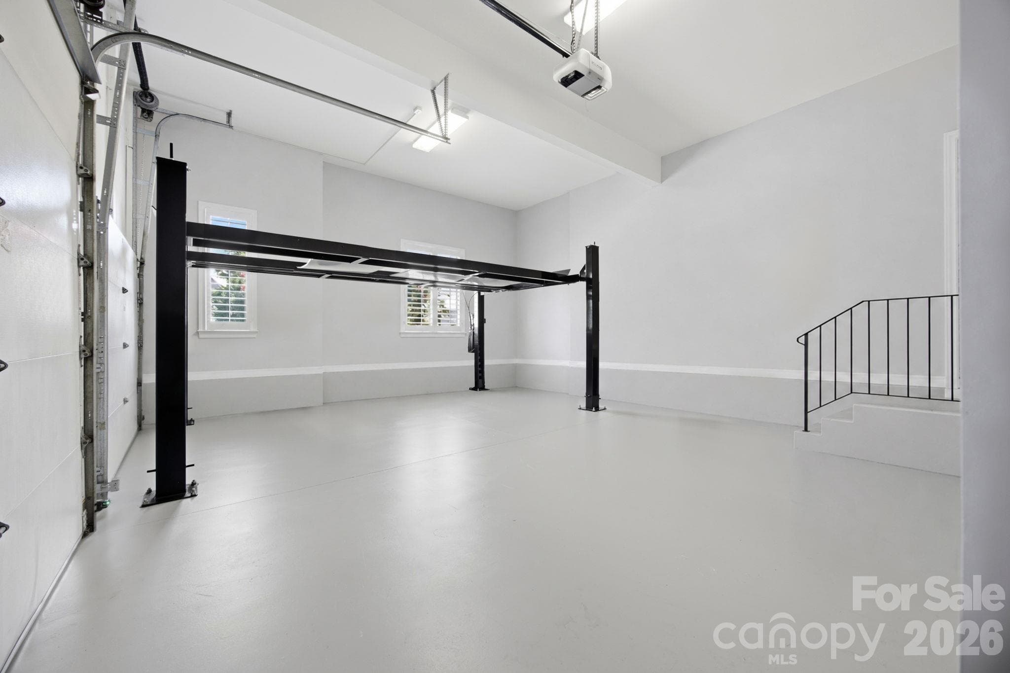 A dream garage setup equipped with a convenient car lift for automotive enthusiasts. - 18416 Peninsula Club Drive, Cornelius