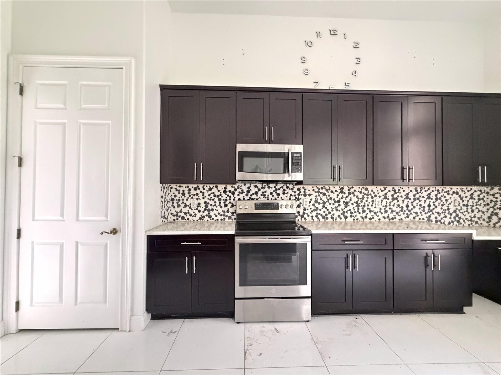 Electric range, microwave, patterned backsplash, and cabinet storage. - 39539 HARBOR HILLS BLVD, LADY LAKE