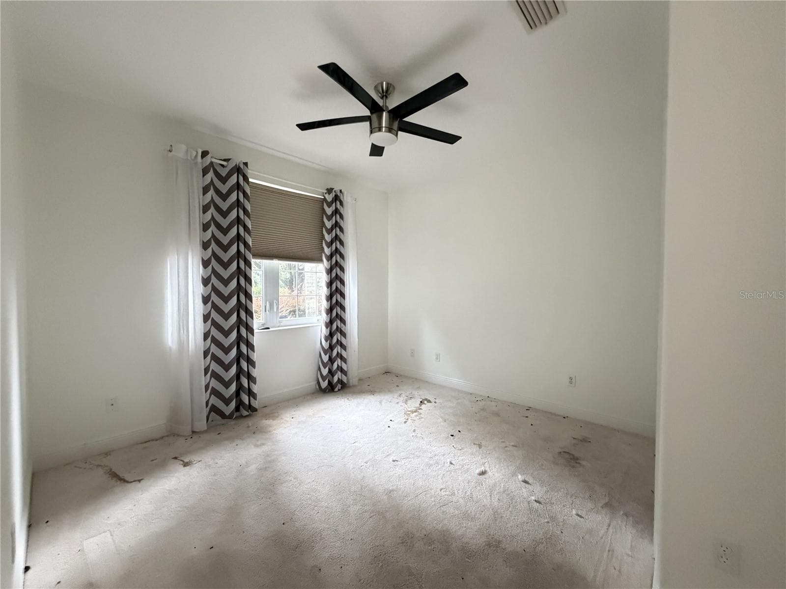Secondary bedroom with ceiling fan, window, and heavily stained carpet. - 39539 HARBOR HILLS BLVD, LADY LAKE
