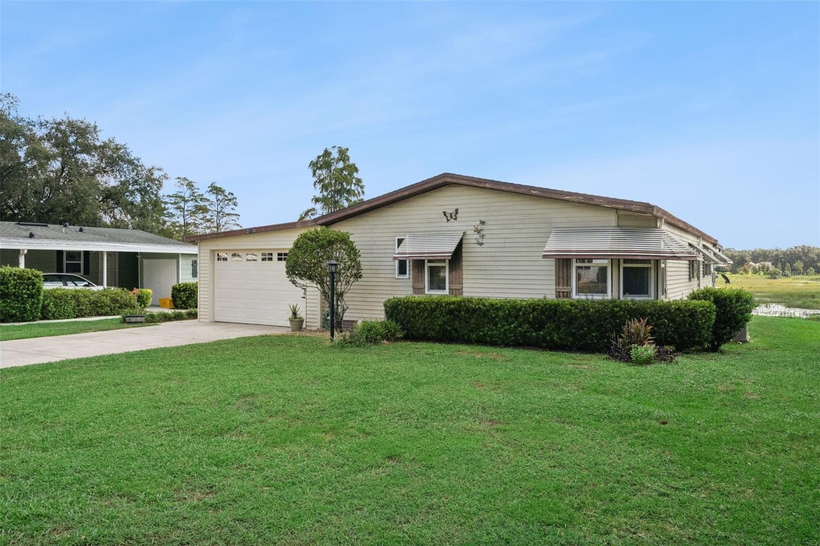 Front and side exterior with manicured hedges and a spacious lawn - 25038 CLIFFORD HL, LEESBURG