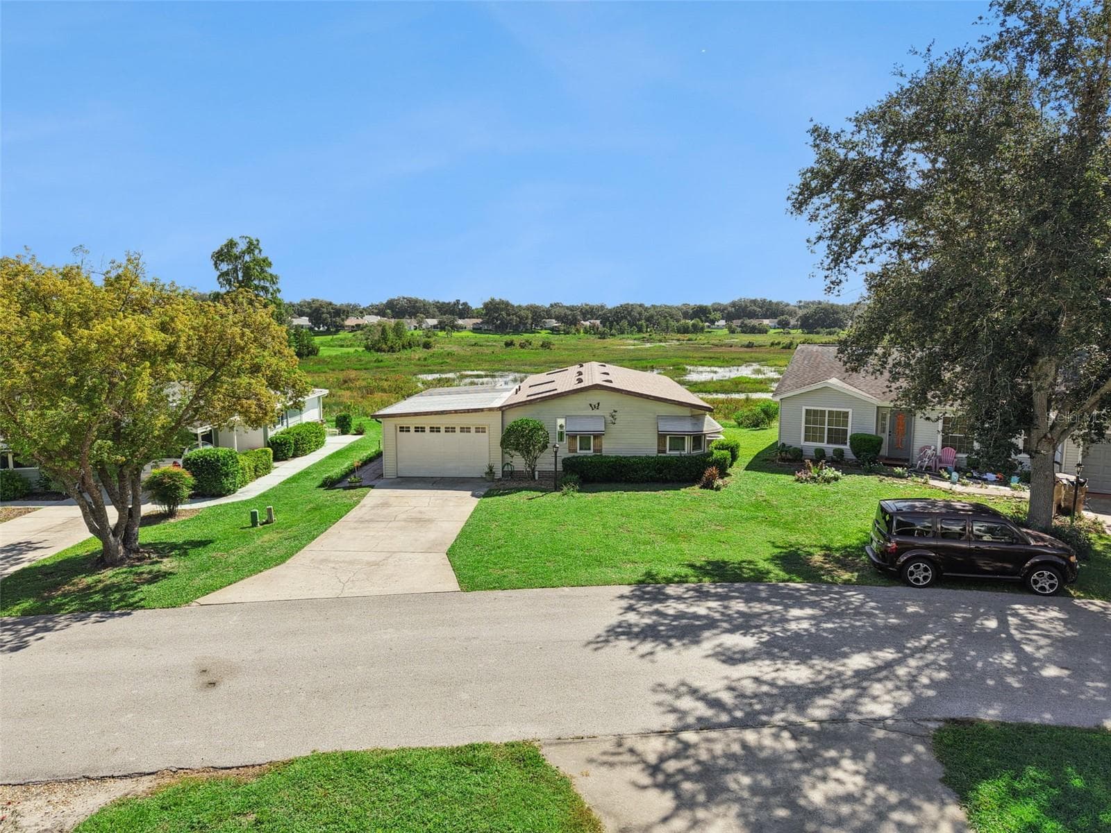 Elevated street view of the home and driveway with the marsh behind - 25038 CLIFFORD HL, LEESBURG