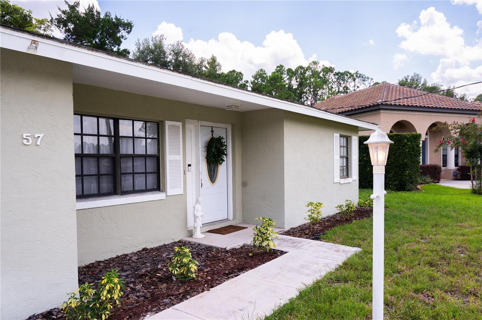 Professional exterior view of the front elevation, showcasing the well-maintained landscaping and inviting entryway. - 57 FORRESTER PL, PALM COAST