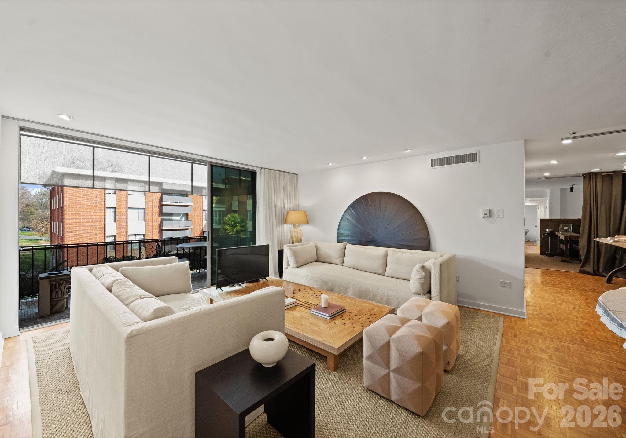 Living room with balcony overlooking 1300 Queens pool and Myers Park landscape. - 1300 Queens Road, Charlotte