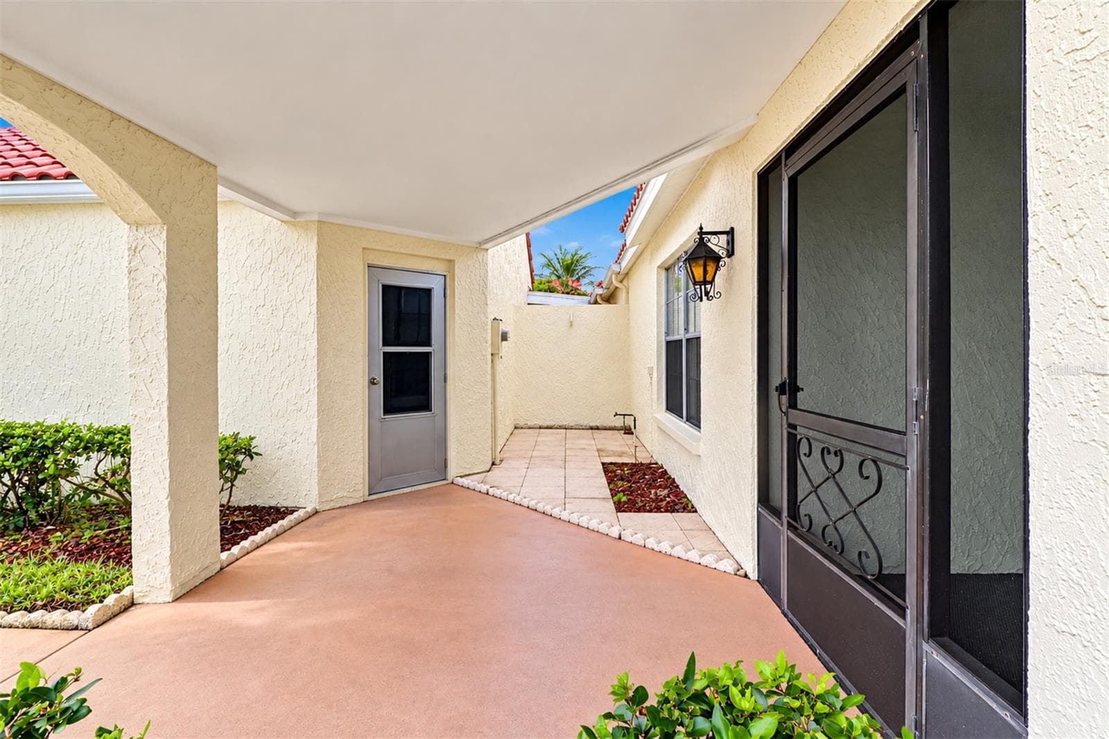 View of the pedestrian door from the garage and the extra patio area in front of the garage wall - 978 MADRID DR, PALM HARBOR