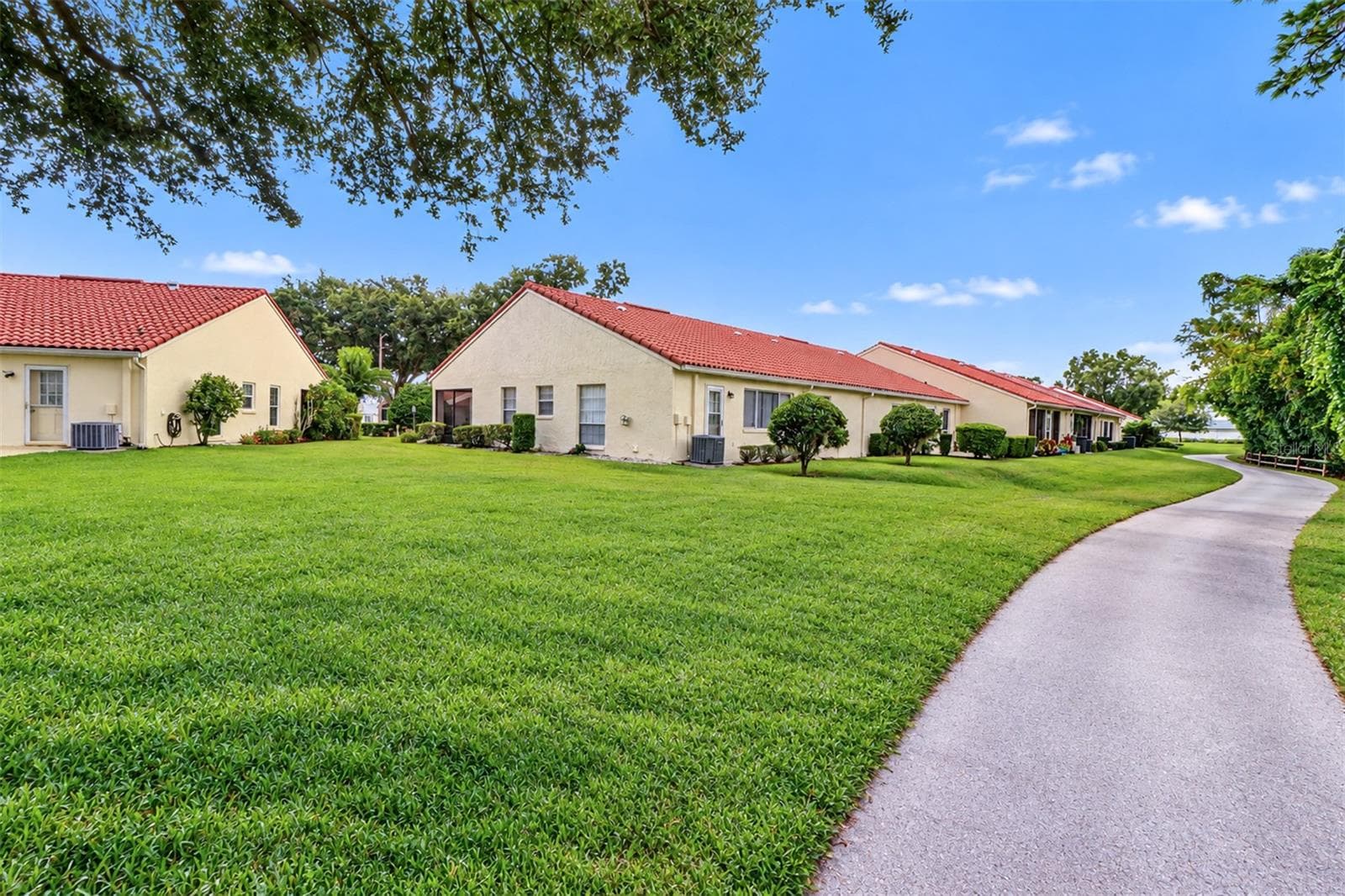 View from the adjacent golf tee looking back at the villa and golf cart path - 978 MADRID DR, PALM HARBOR