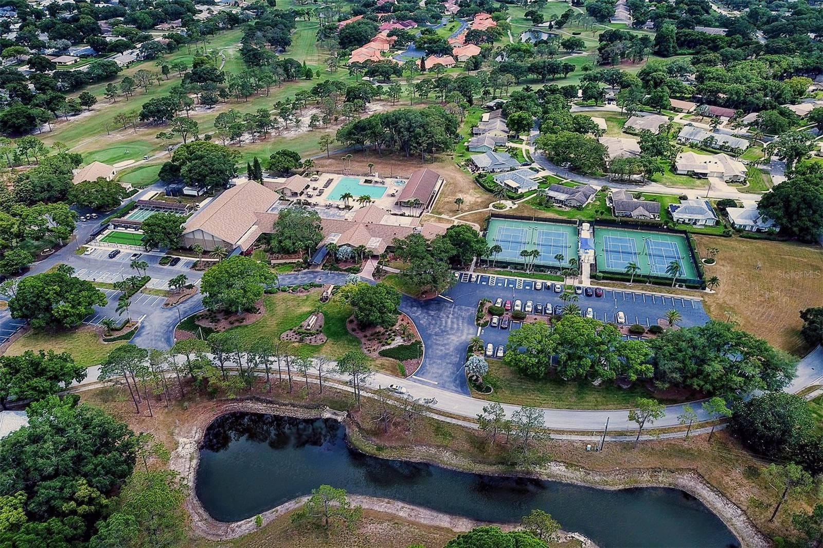 Aerial view of the golf club on the left, the main clubhouse and the tennis courts to the right - 978 MADRID DR, PALM HARBOR