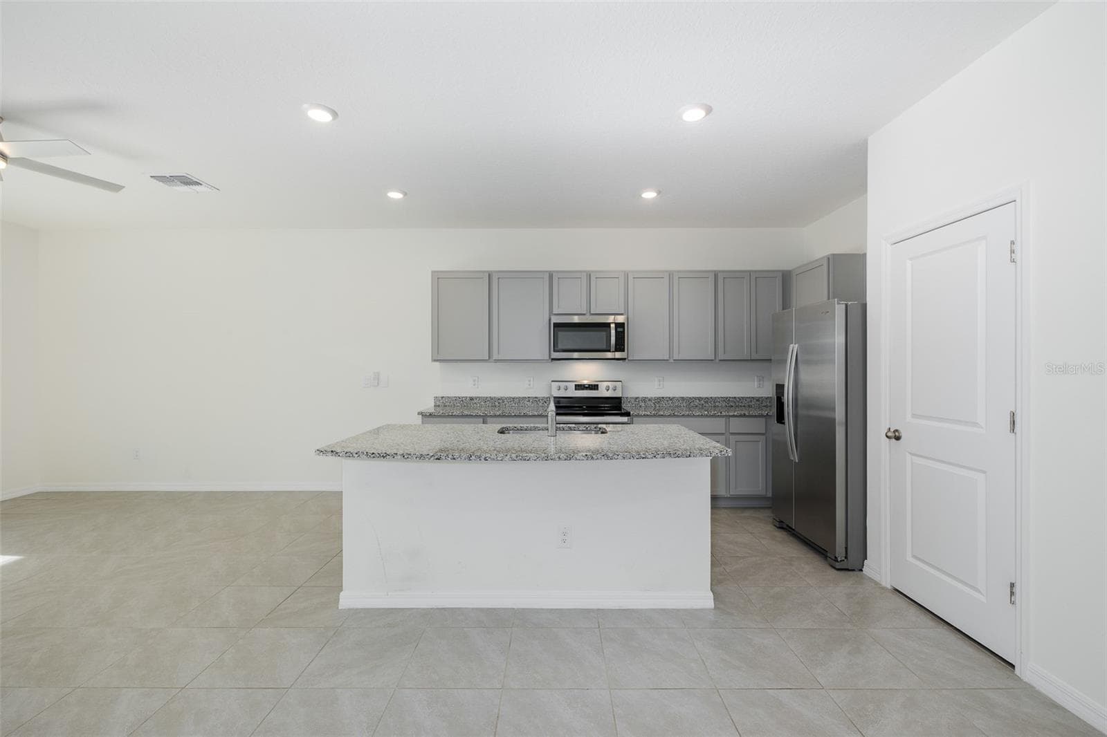 Crisp gray shaker-style cabinetry pairs beautifully with granite countertops and stainless-steel appliances for a fresh, contemporary feel - 11166 CRESCENT DEER DR, LAND O LAKES