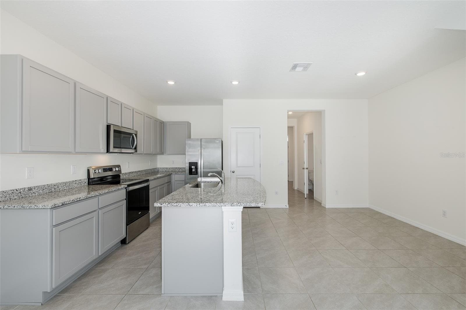 Modern, open-concept kitchen featuring granite countertops, stainless-steel appliances, gray cabinetry and a spacious center island - 11166 CRESCENT DEER DR, LAND O LAKES