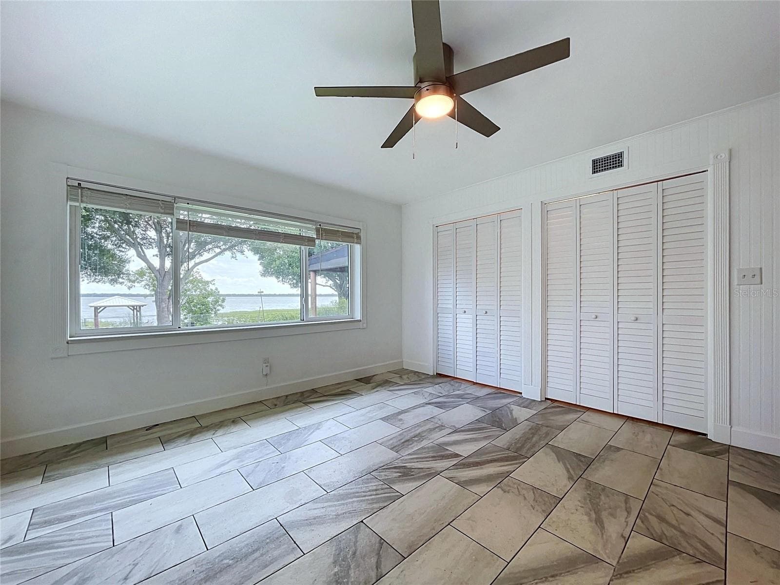 Bedroom 1 with ceiling fan and tile-pattern flooring - 1348 EDGEWATER BEACH DR, LAKELAND